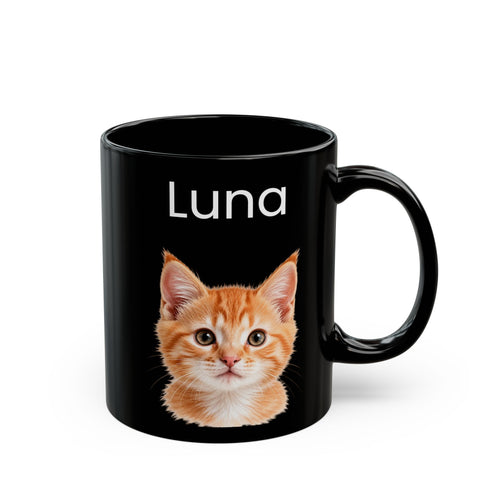 A black ceramic mug with a glossy finish, featuring the name 'Luna' in white text above a printed illustration of an orange tabby kitten. The mug is shown on a clean white background.