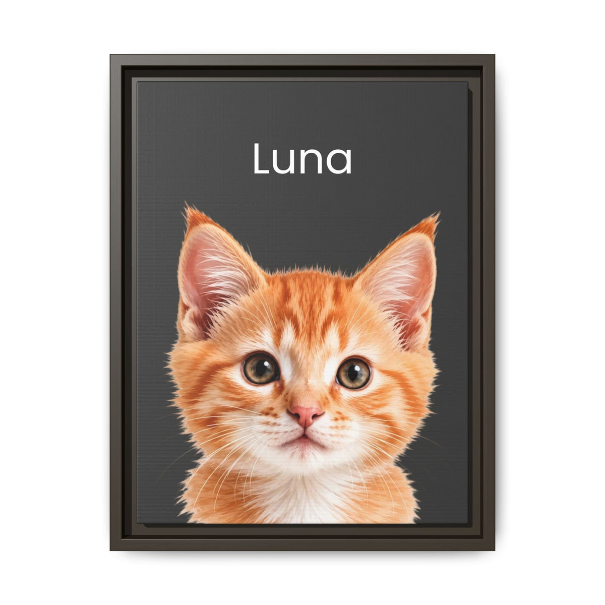A framed custom pet portrait featuring a close-up photo of an orange tabby kitten on a dark charcoal background with the name 'Luna' printed in white at the top. The print is housed in a dark brown frame and is shown against a clean white background.
