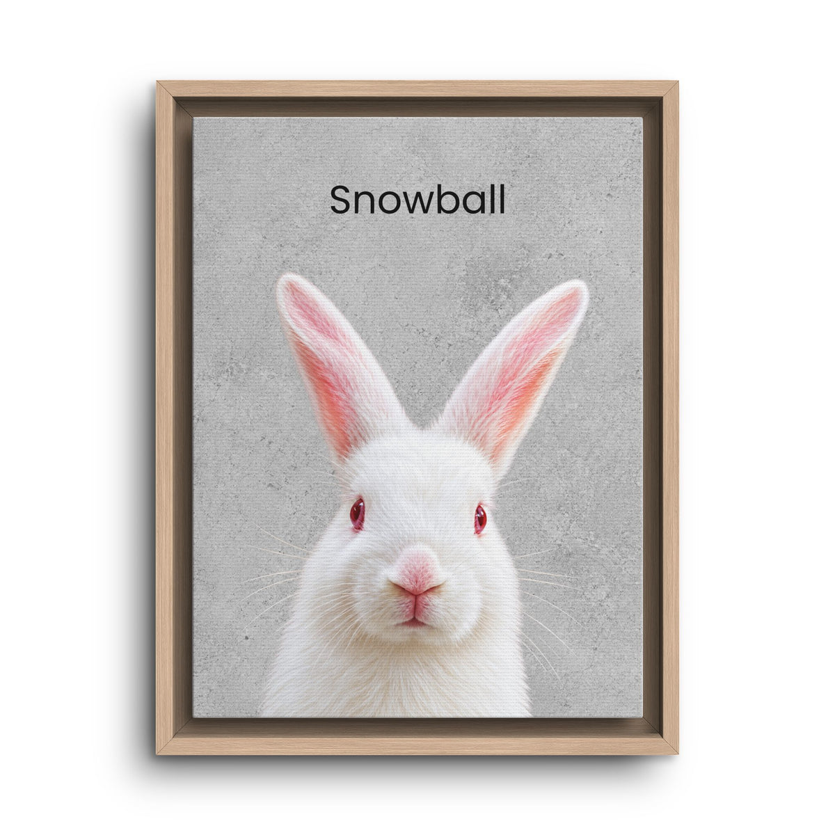 Framed art print featuring a white rabbit with red eyes and pink inner ears on a textured gray background, with the word 'Snowball' printed above. The print is housed in a light natural wood frame and shown against a plain white background.
