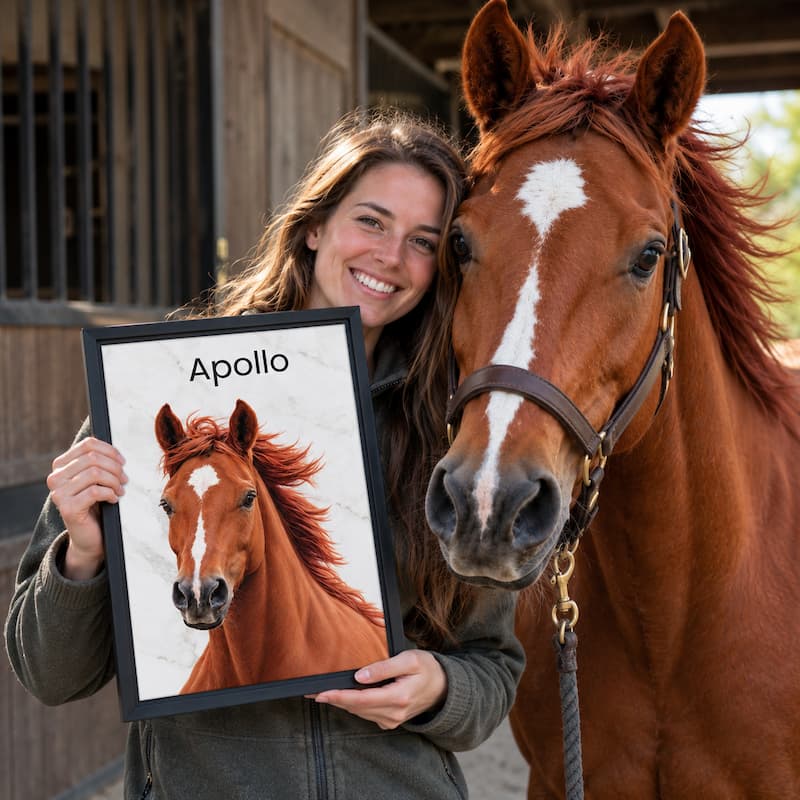 A smiling woman stands beside a brown horse in front of a stable, holding up a framed portrait print of the horse with the name 'Apollo' at the top.